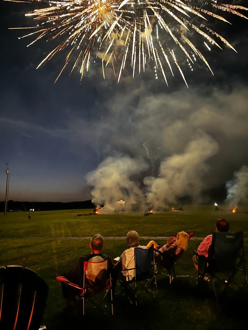 Massive gold fireworks burst with smoke clouds over open field